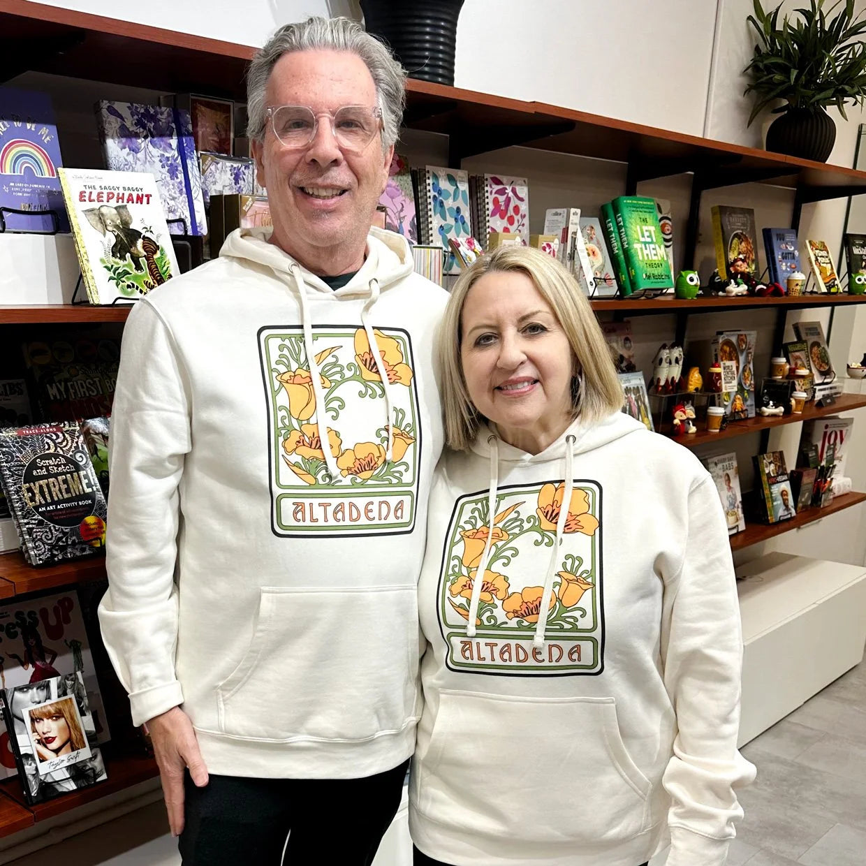 Two people wearing white Altadena Poppy hoodies in the store