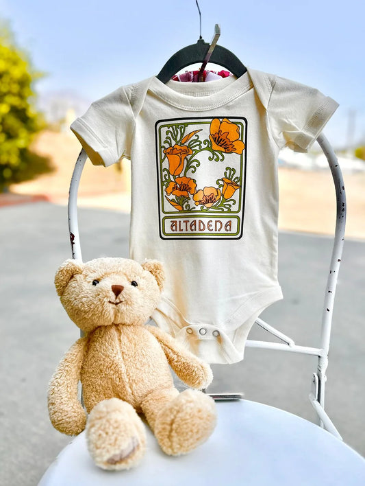 Altadena Poppy baby onesie displayed with a teddy bear