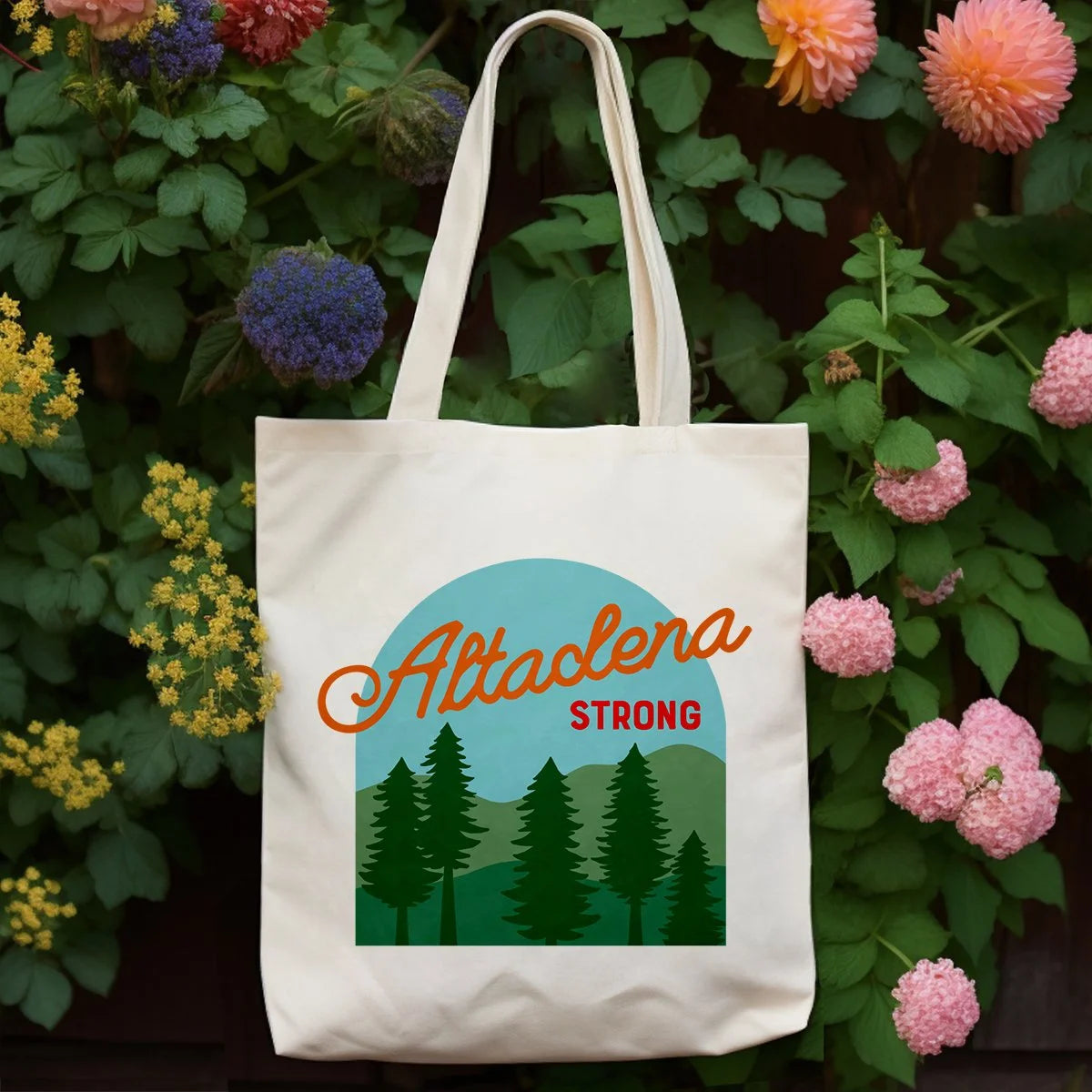 Altadena Strong tote bag displayed among flowers