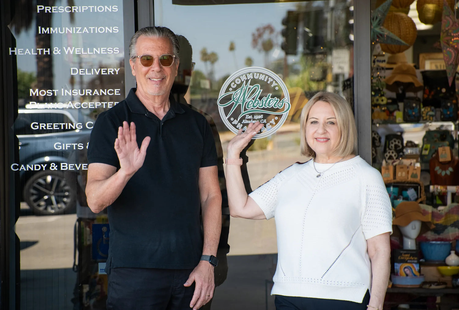Webster's Community Pharmacy team members waving outside the store.