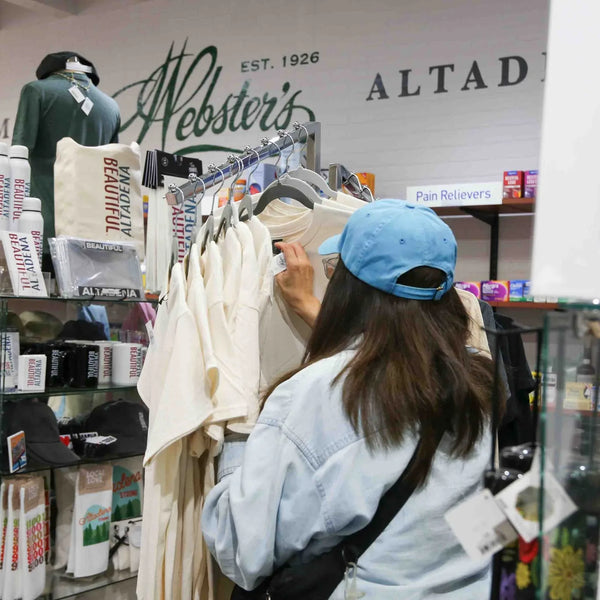 Customer browsing Webster's branded apparel beneath the Est. 1926 sign in the Altadena store