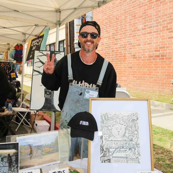 Artist flashing a peace sign at his print booth at Webster's 100th anniversary fair