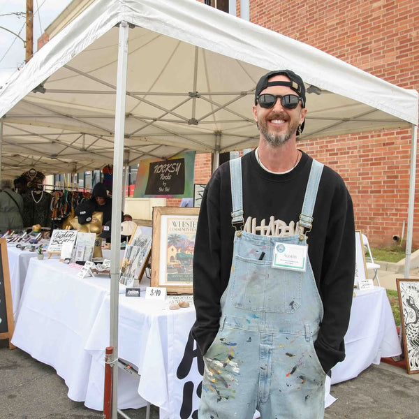 Artist in overalls at the Really Good Art booth at Webster's street fair
