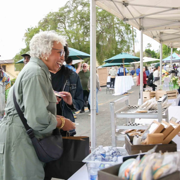 Guests browsing baked goods at a vendor tent during Webster's anniversary fair
