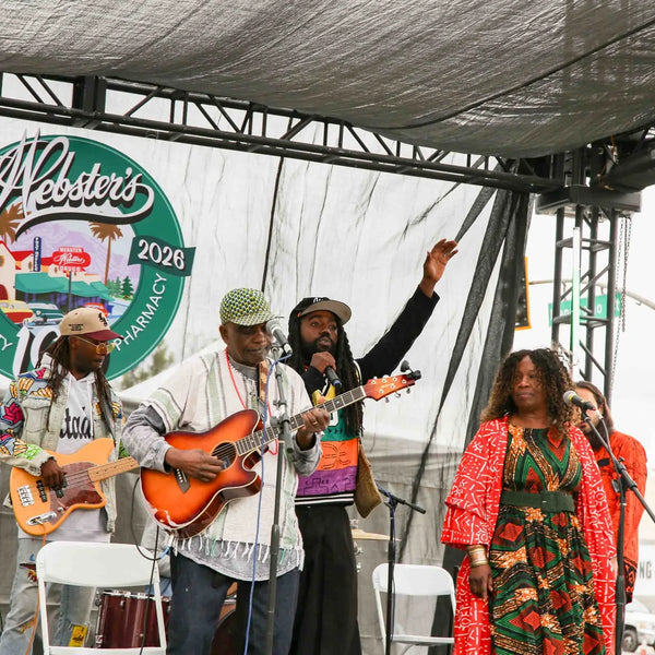 Band performing with guitars beneath the Webster's centennial logo