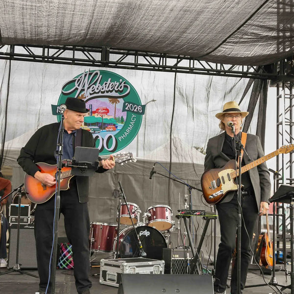 Band performing with guitars and drums at Webster's centennial stage