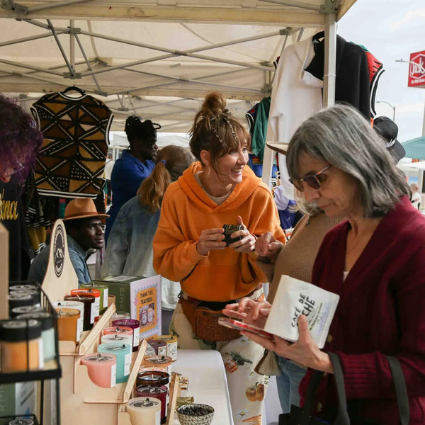 Shoppers sampling candles at a vendor booth during Webster's street fair