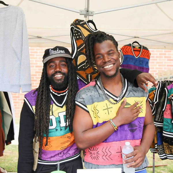 Two clothing vendors embracing at their booth during Webster's anniversary fair