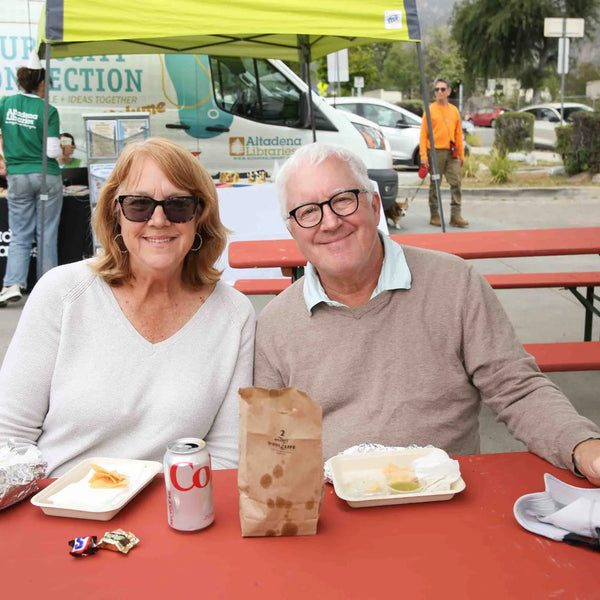 Couple sharing breakfast at a picnic table at Webster's 100th anniversary fair in Altadena