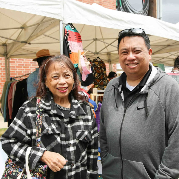 Smiling couple in front of clothing racks at Webster's centennial street fair