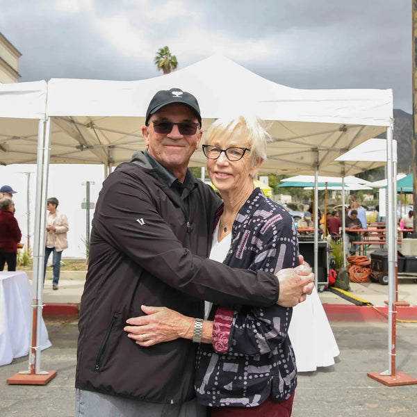 Couple hugging near the white festival tents at Webster's anniversary fair