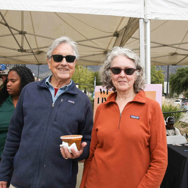 Couple smiling beneath a booth canopy at Webster's anniversary fair in Altadena