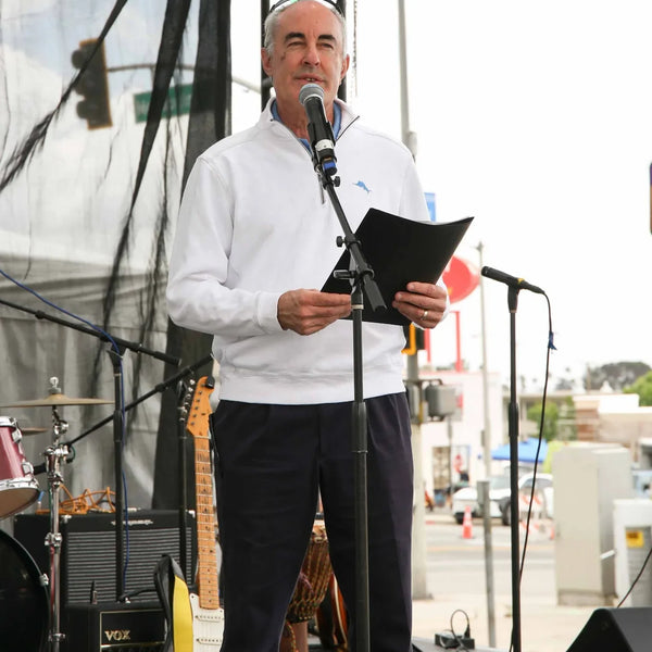 Emcee reading remarks on stage at Webster's 100th anniversary street fair in Altadena