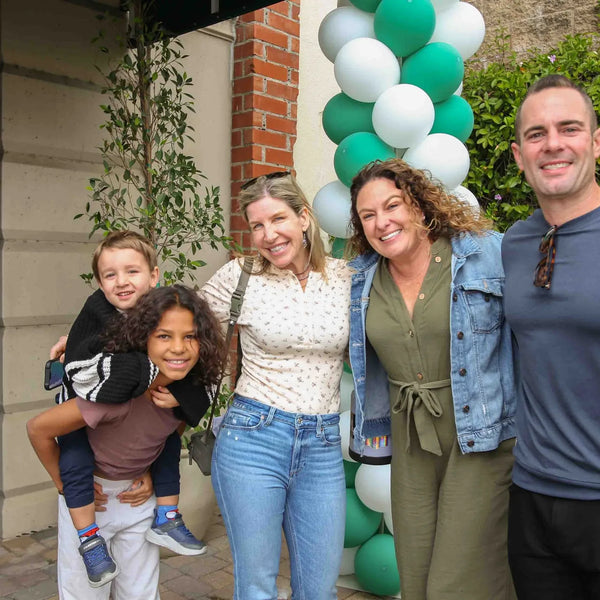 Family posing beneath the green and white balloons at Webster's street fair