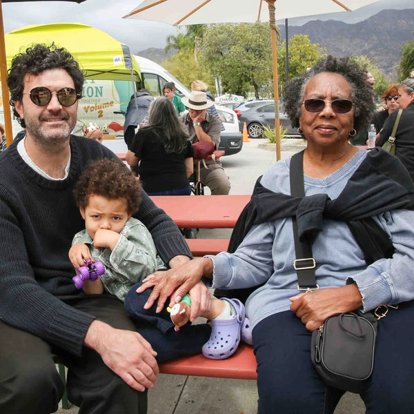 Family with grandmother relaxing at a picnic table during Webster's street fair