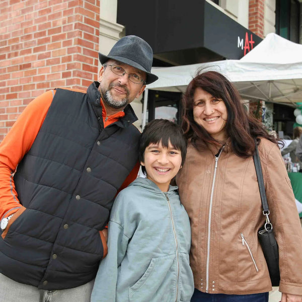 Family of three posing at Webster's centennial street fair in Altadena