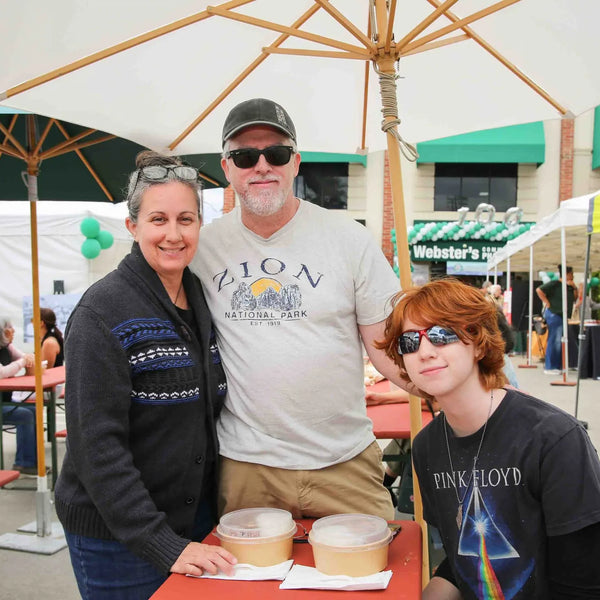 Family relaxing at a picnic table at Webster's 100th anniversary street fair