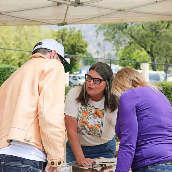 Visitors browsing prints at a vendor booth during Webster's 100th anniversary street fair