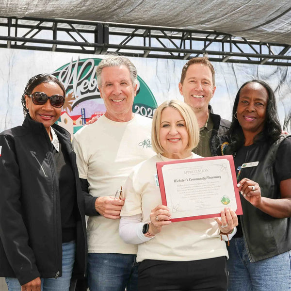 Group holding a framed certificate honoring Webster's Community Pharmacy's 100 years