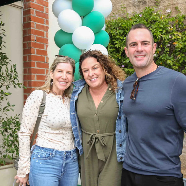 Three friends posing by the balloon arch at Webster's centennial celebration
