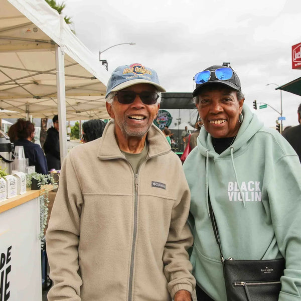 Two friends smiling by the Cafe de Leche cart at Webster's anniversary celebration