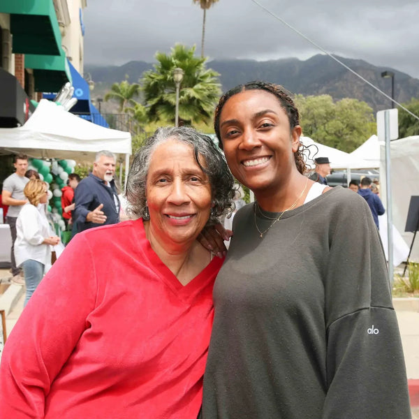 Two friends embracing near the art booths at Webster's 100th anniversary celebration