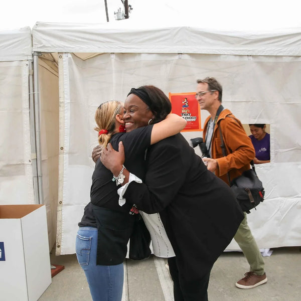 Friends hugging by the Greek Cafe stand at Webster's anniversary street fair