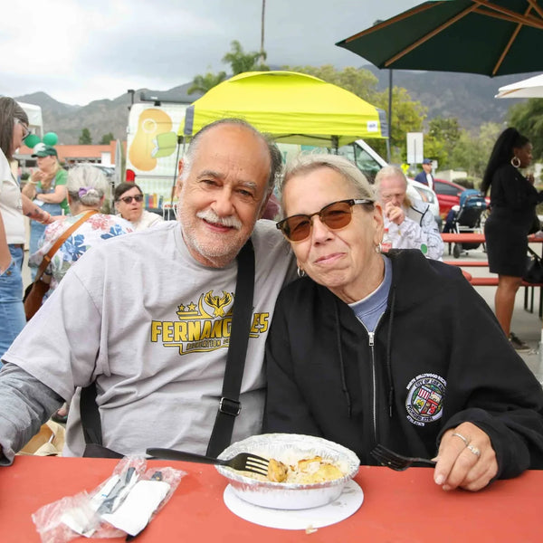 Two friends sharing lunch at a picnic table during Webster's centennial fair