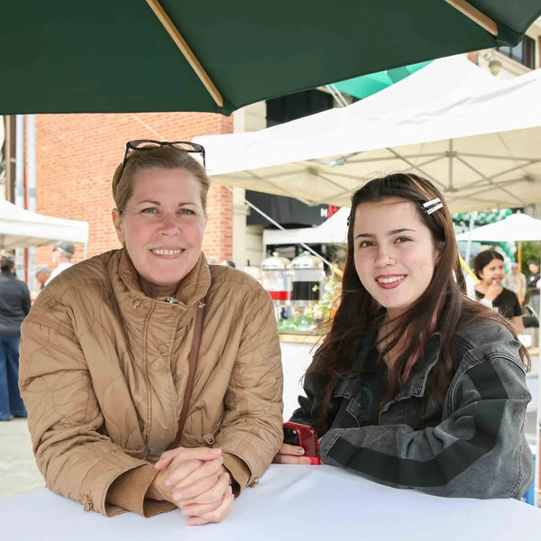 Two friends at an umbrella table at Webster's centennial street fair