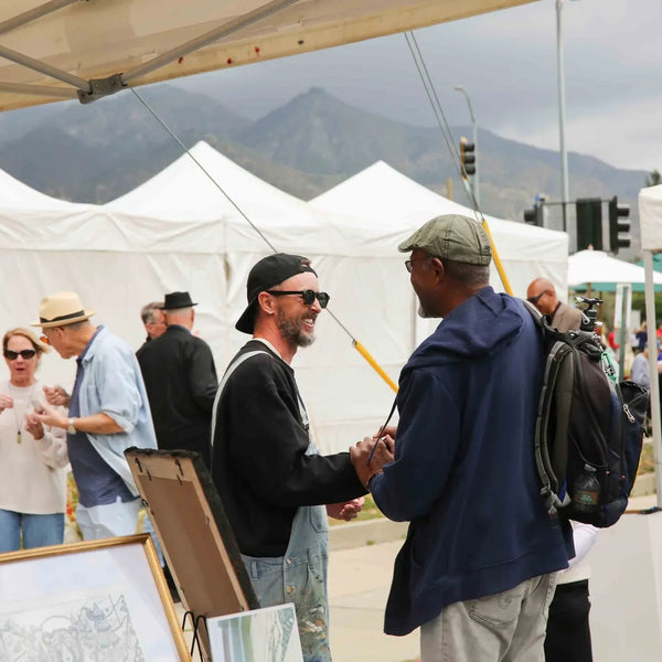 Attendees greeting each other along the art vendor row at Webster's street fair