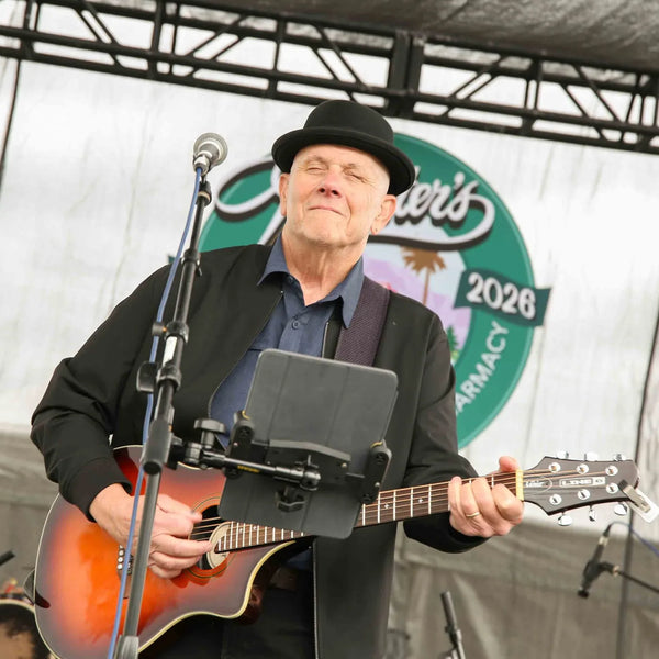Guitarist singing beneath the Webster's anniversary logo on stage