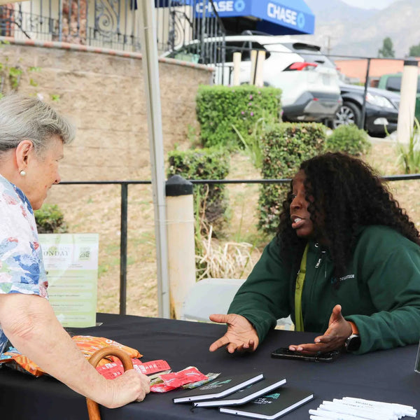Guest chatting with a representative at an outdoor info table at Webster's street fair in Altadena