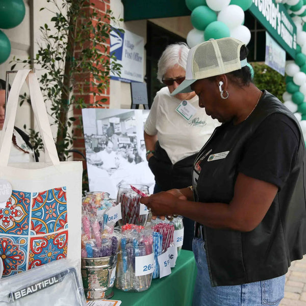 Shoppers browsing Webster's anniversary merchandise table decorated with balloons