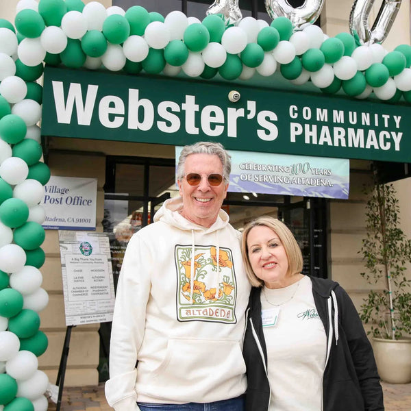Webster's owners beneath the balloon arch at the Community Pharmacy storefront