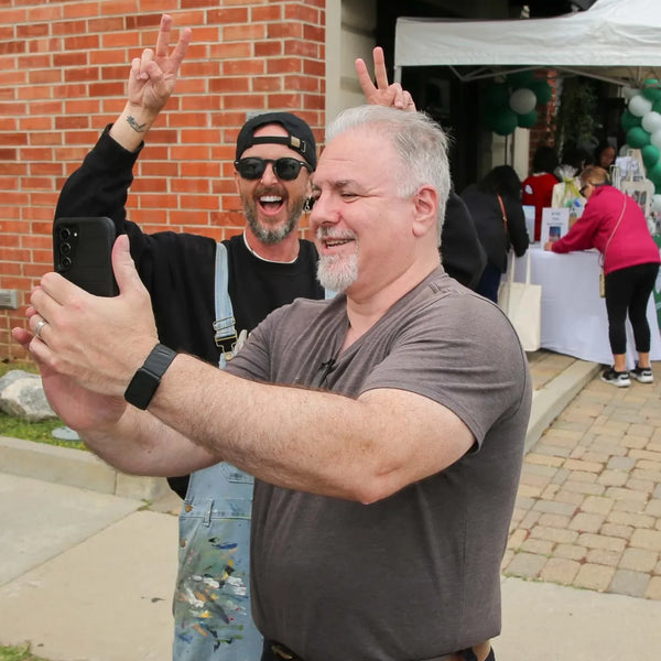 Two guests flashing peace signs for a selfie at Webster's anniversary street fair