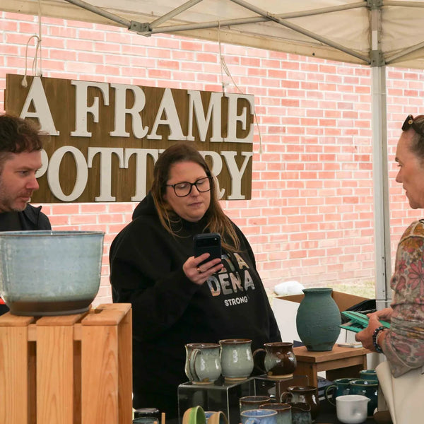 A Frame Pottery vendors chatting with a shopper at Webster's 100th anniversary fair