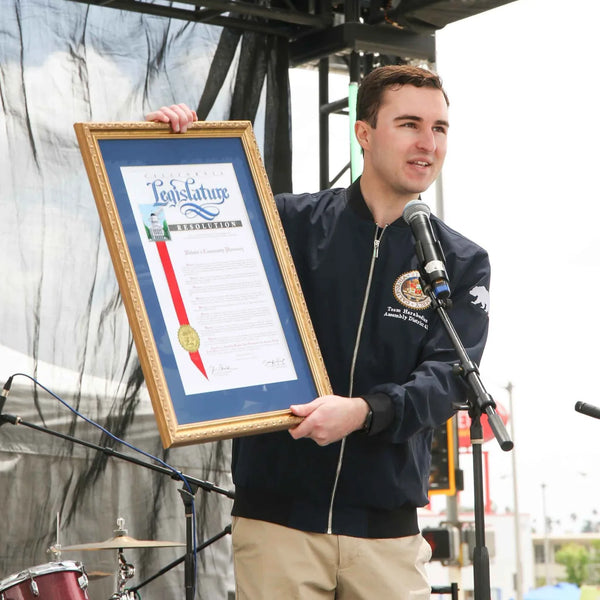 Official presenting a framed proclamation honoring Webster's Pharmacy centennial