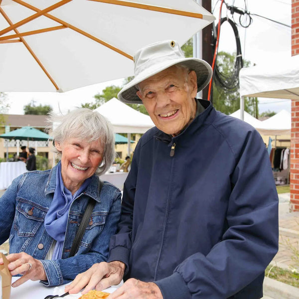 Senior couple smiling at an umbrella table during Webster's street fair