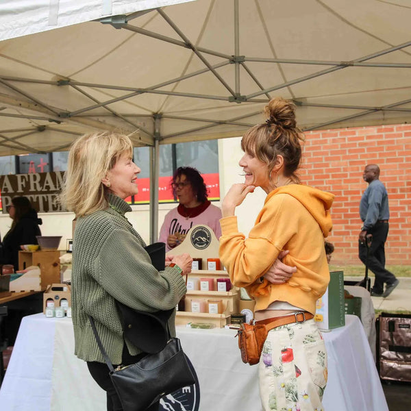 Shoppers chatting at a craft vendor table during Webster's anniversary fair