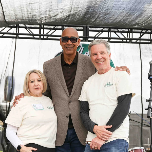 Three guests posing together on stage at Webster's Pharmacy centennial event