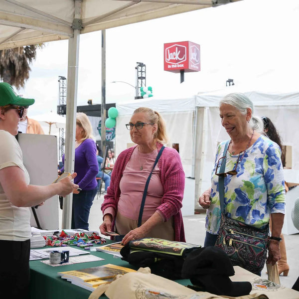 Attendees gathering at a vendor booth during Webster's Pharmacy 100th anniversary street fair