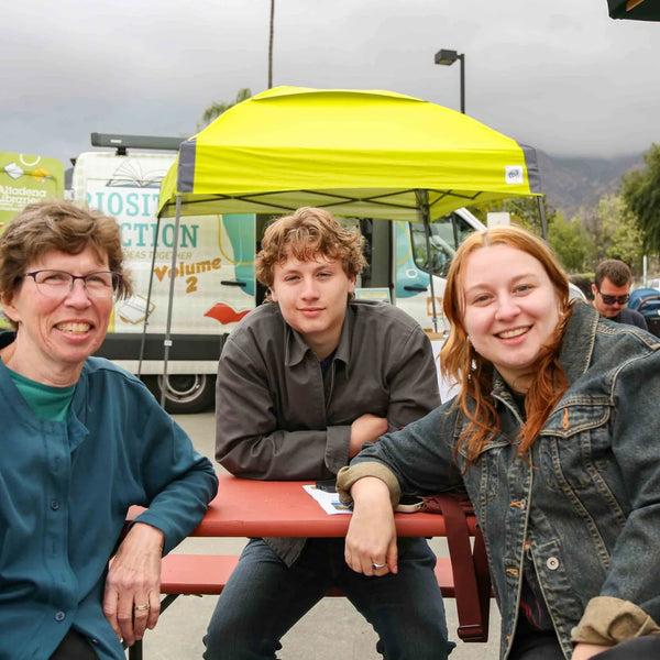 Three friends on a picnic bench at Webster's 100th anniversary fair