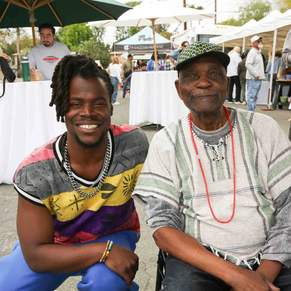 Two friends smiling among the umbrella tables at Webster's centennial street fair