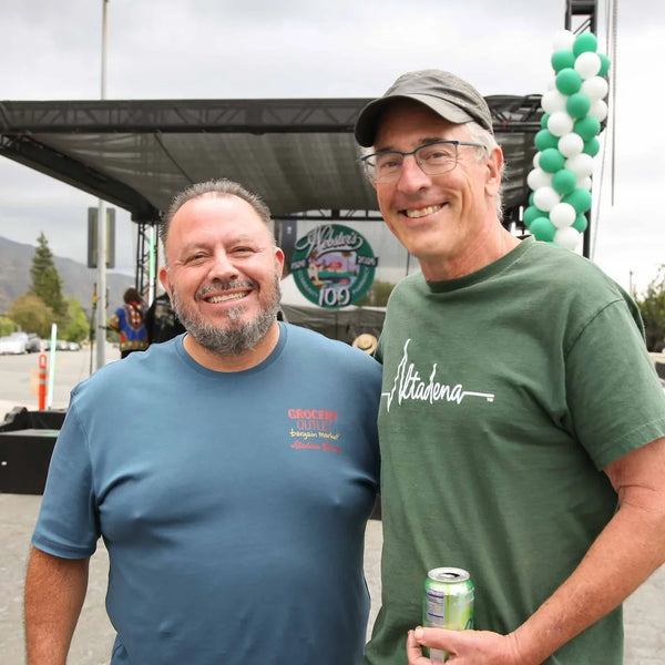 Two friends with drinks near the stage at Webster's 100th anniversary fair
