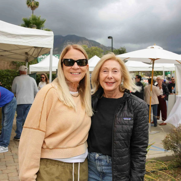 Two friends smiling near the booths at Webster's 100th anniversary fair