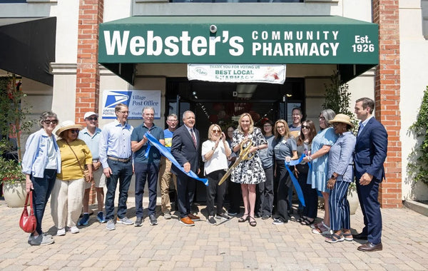 Officials and neighbors cutting the ribbon under the Webster's Community Pharmacy awning.